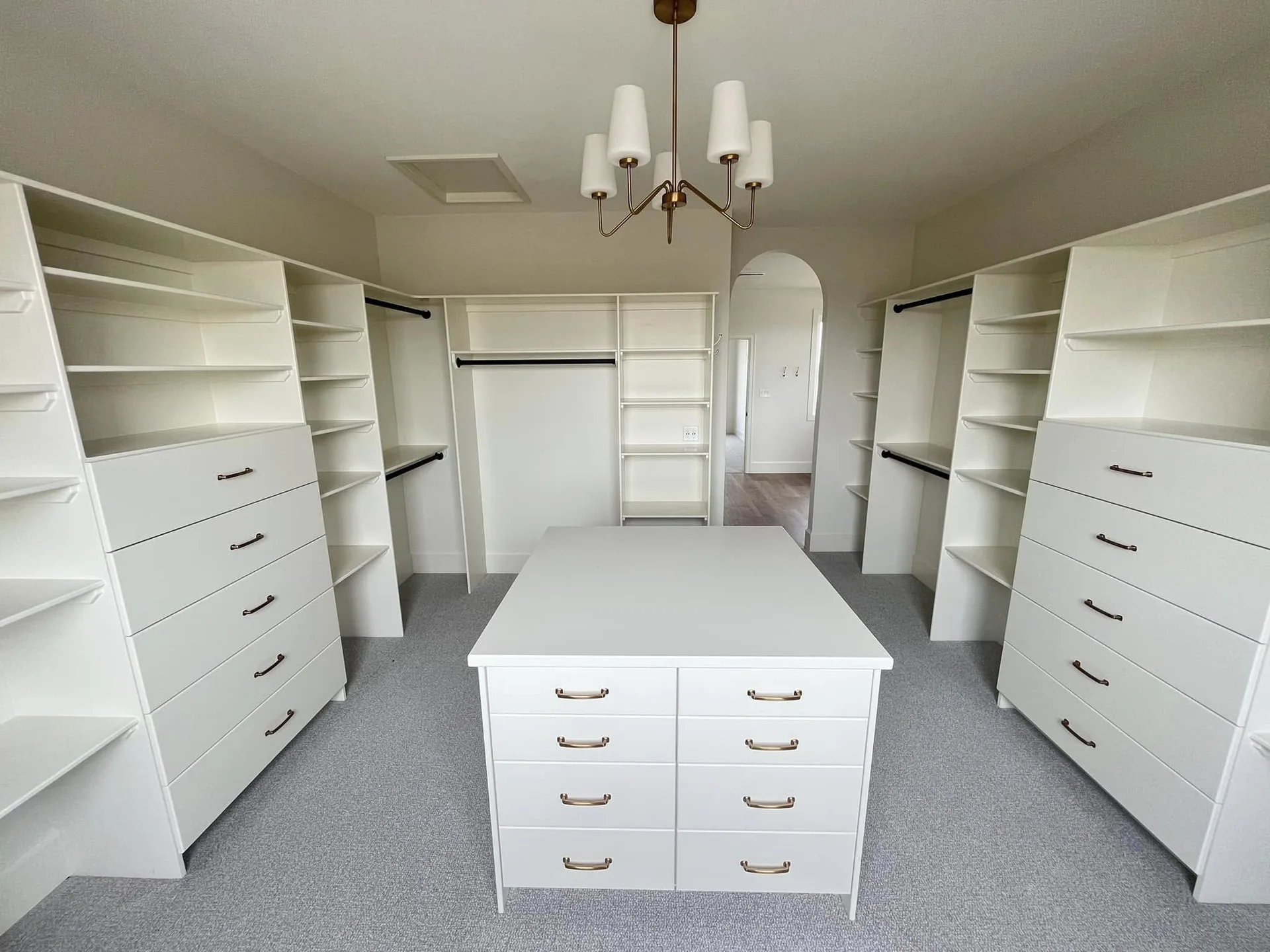 Finished walk-in wardrobe with fitted shelving, drawers and a central storage island