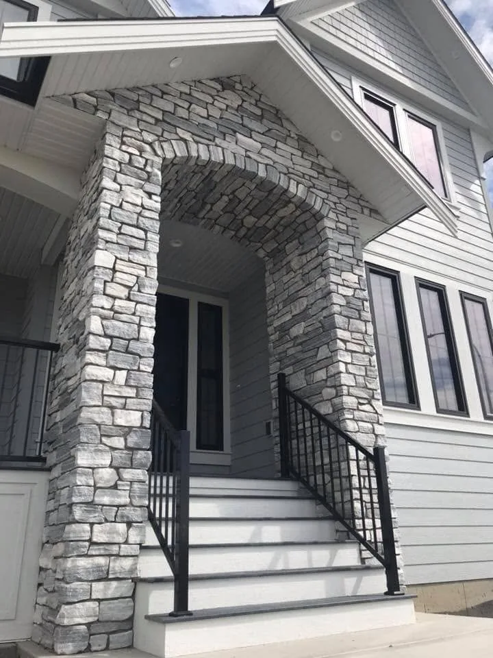 Stone archway and black-railed steps at the front entry