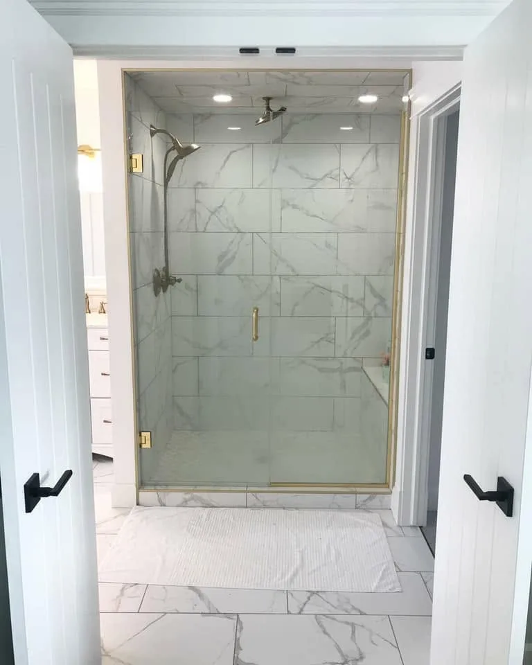 Glass walk-in shower with marble-look tile and brass fixtures