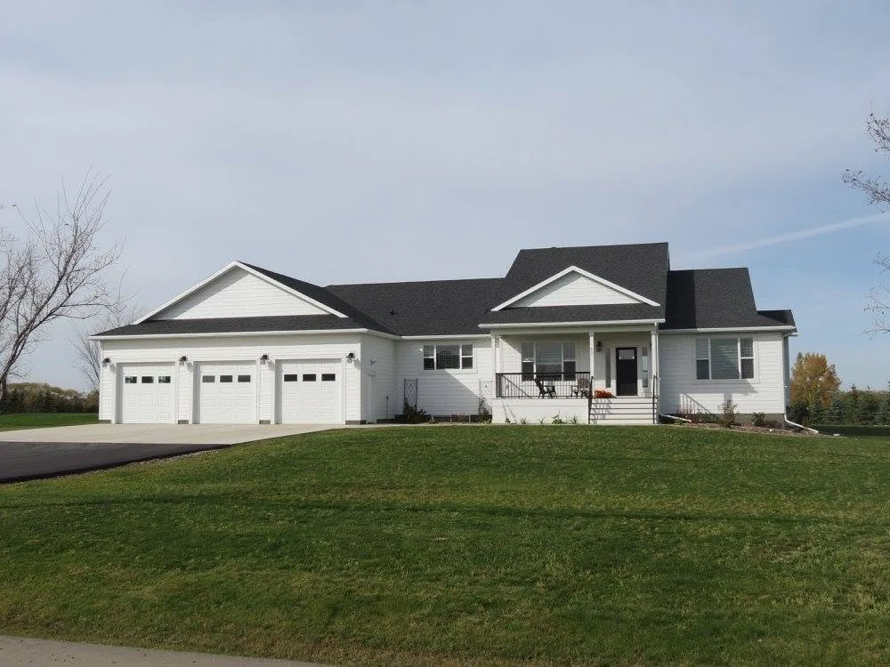 Finished white bungalow with a covered porch, dark roof and broad green lawn