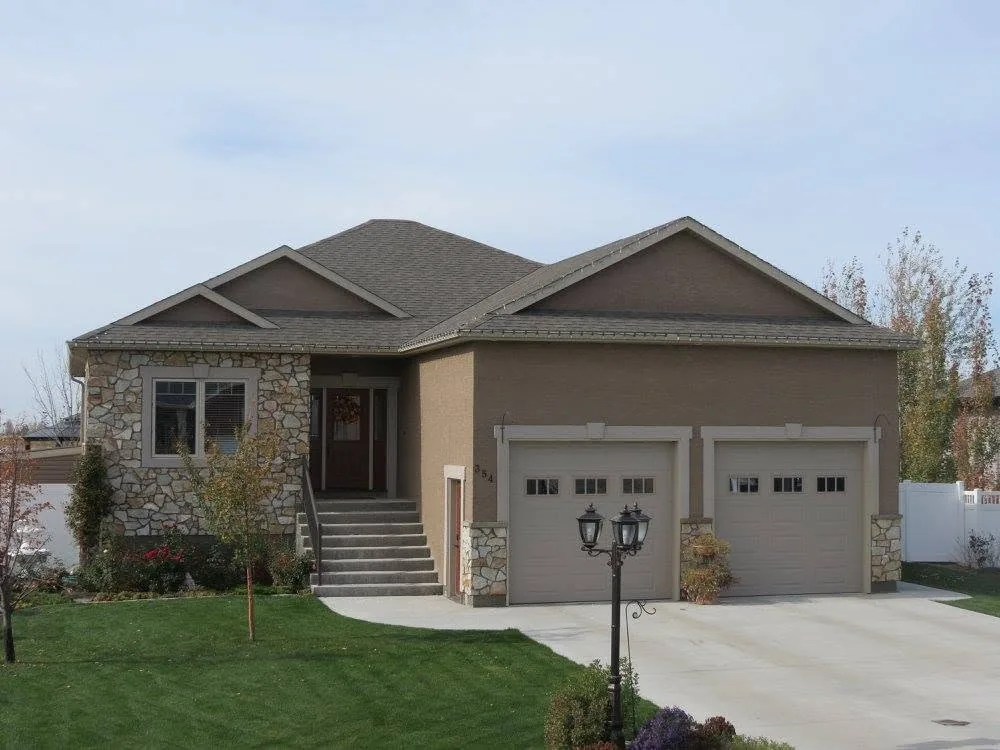 Finished single-storey home with neutral siding, stone accents and a double garage