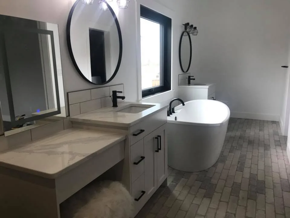 Finished bathroom with twin round mirrors, a long vanity and a freestanding bathtub