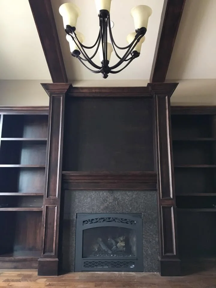 Dark timber fireplace surround with built-in shelves and ceiling beams