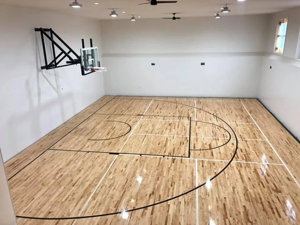 Elevated view of an indoor basketball court with pale walls and polished wood flooring
