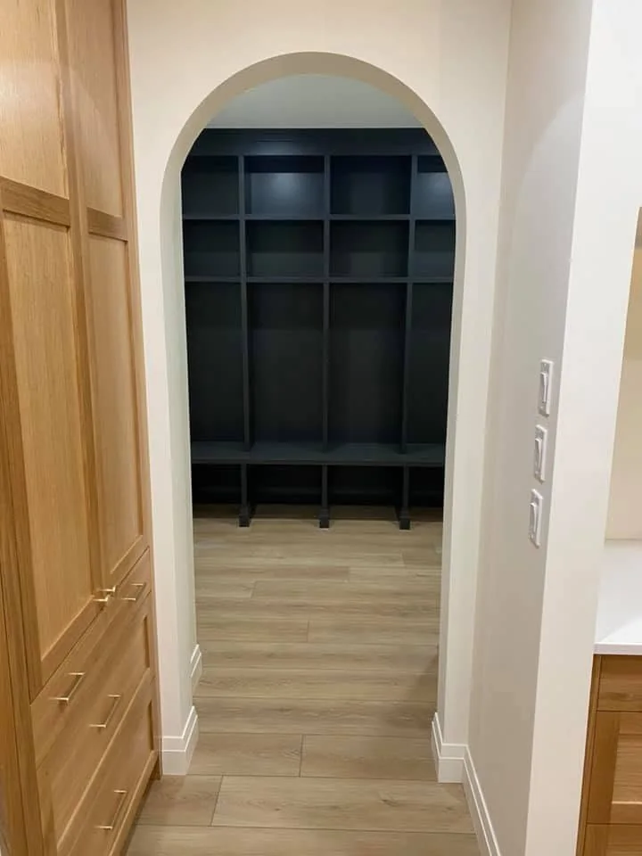 Arched doorway leading to dark built-in storage cubbies and a bench