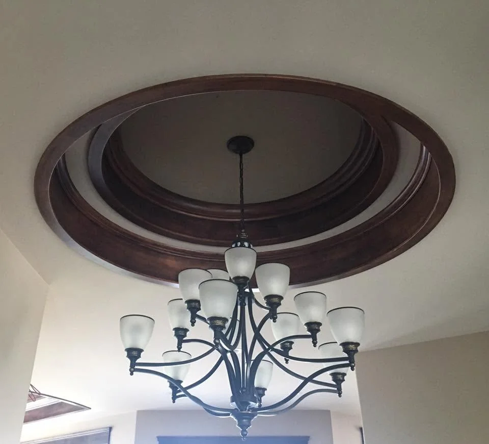 Chandelier beneath concentric rings of dark timber ceiling trim