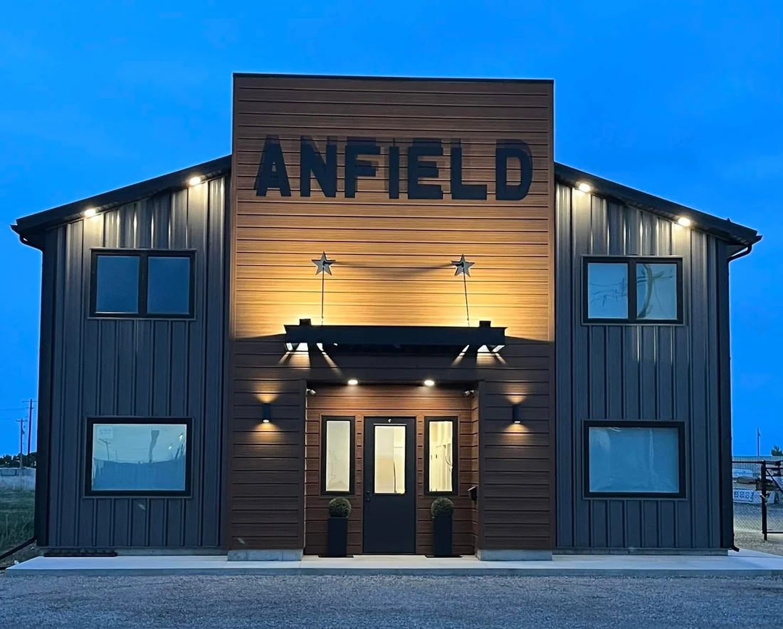 Anfield building exterior at dusk, with illuminated entrance and ANFIELD lettering