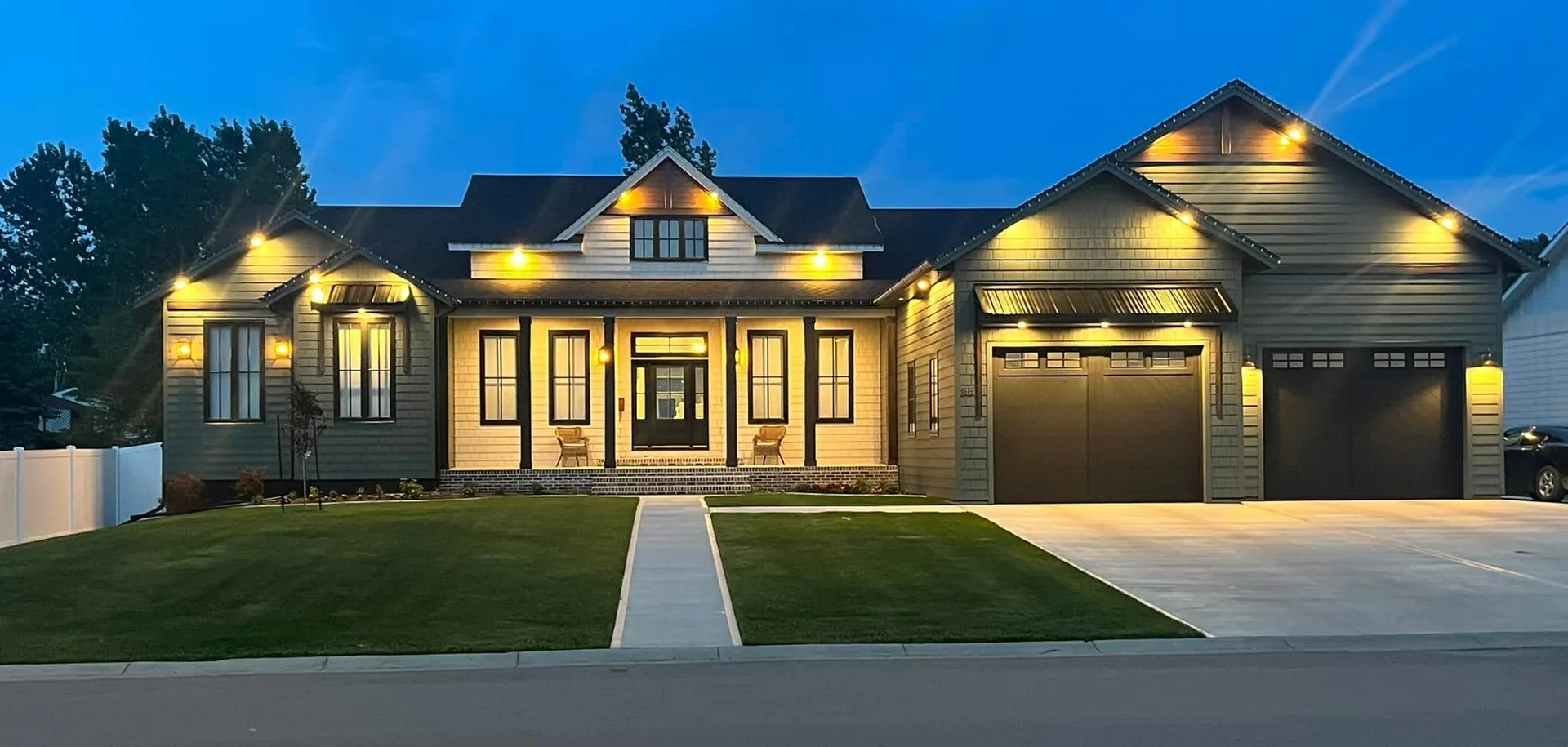 Completed home with illuminated gables, landscaped lawn and a welcoming front porch