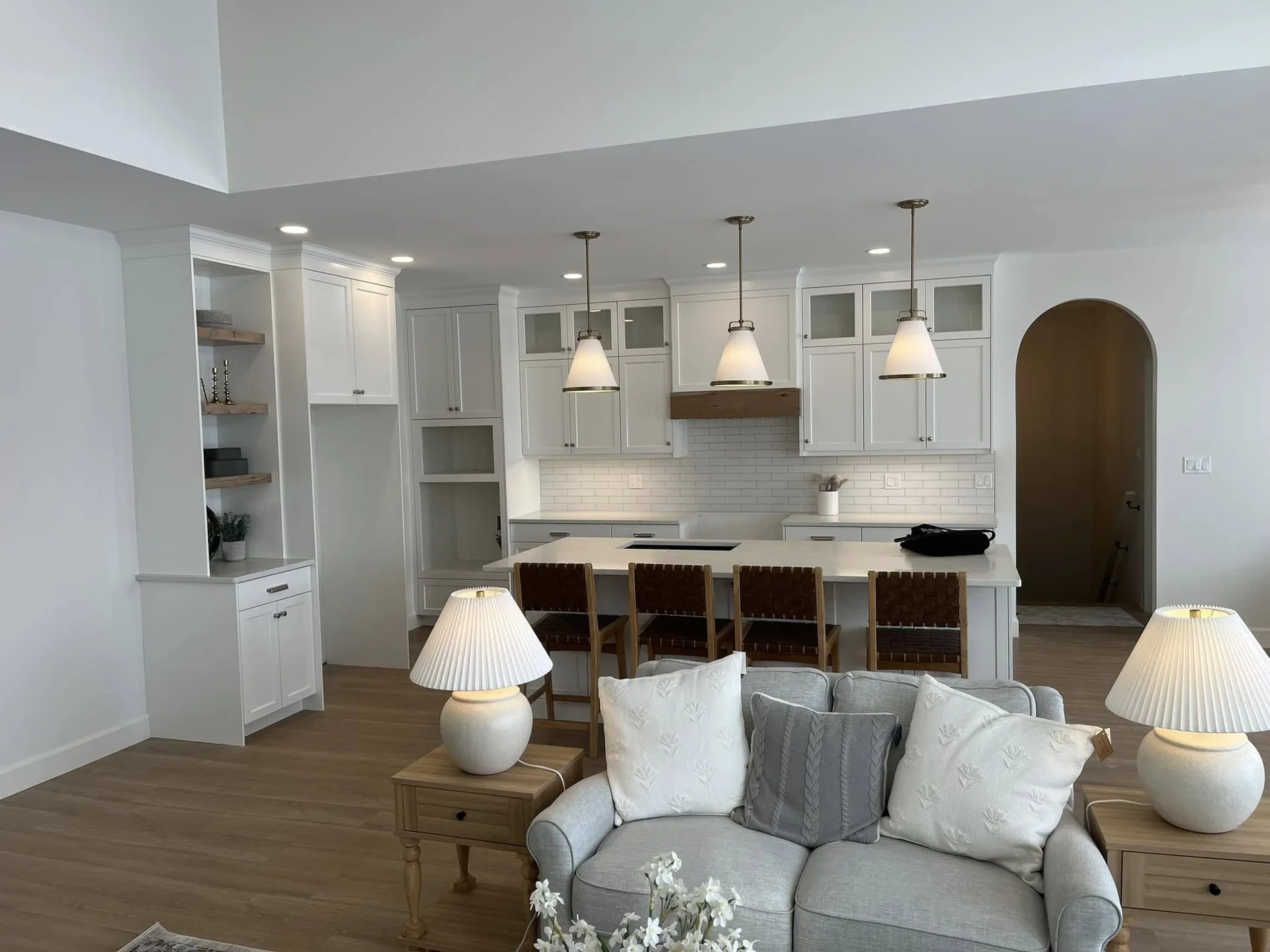 White kitchen with timber accents and pendant lighting opening onto a furnished living space