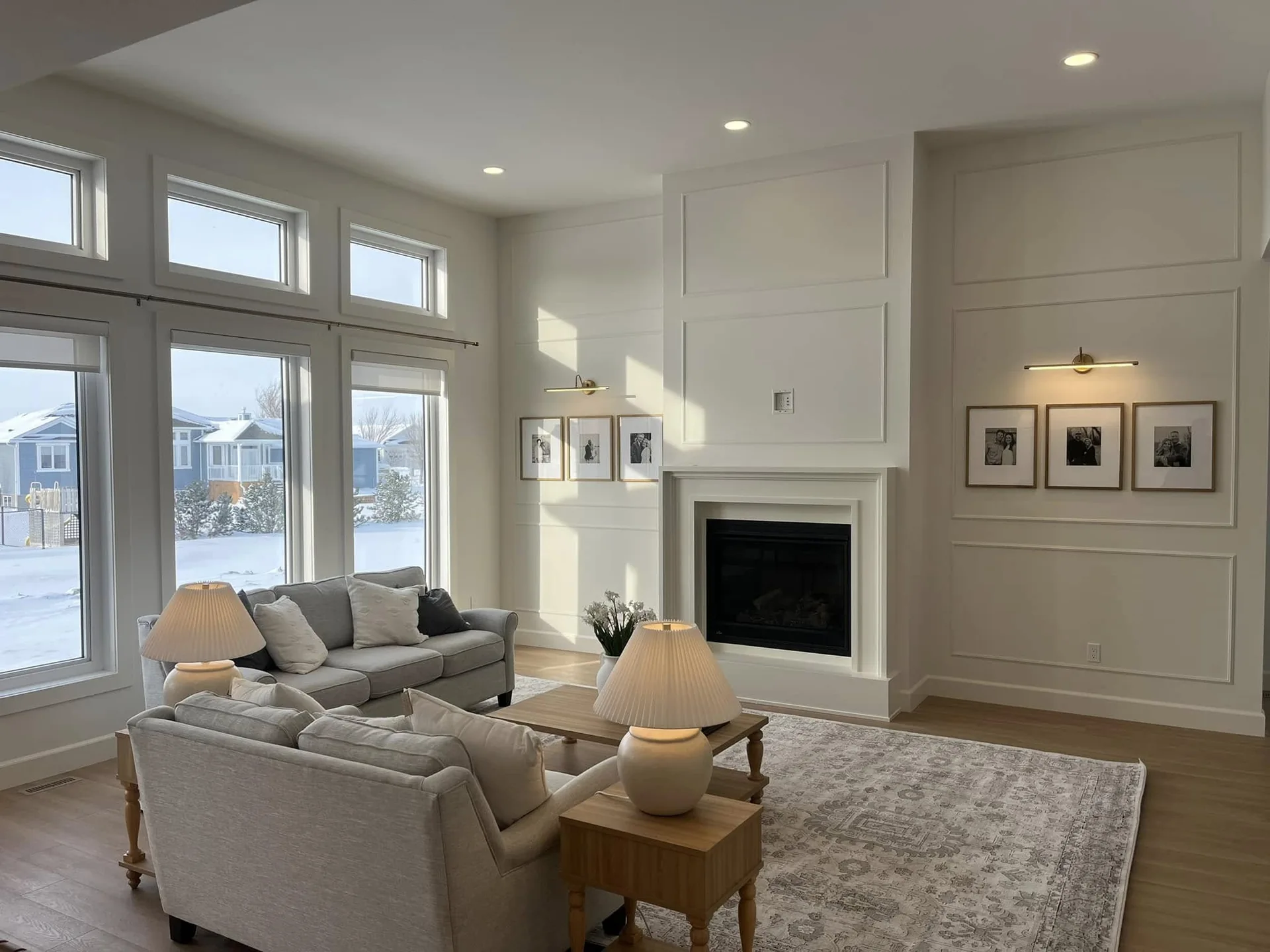 Sunlit furnished living room with tall windows and a white panelled fireplace wall