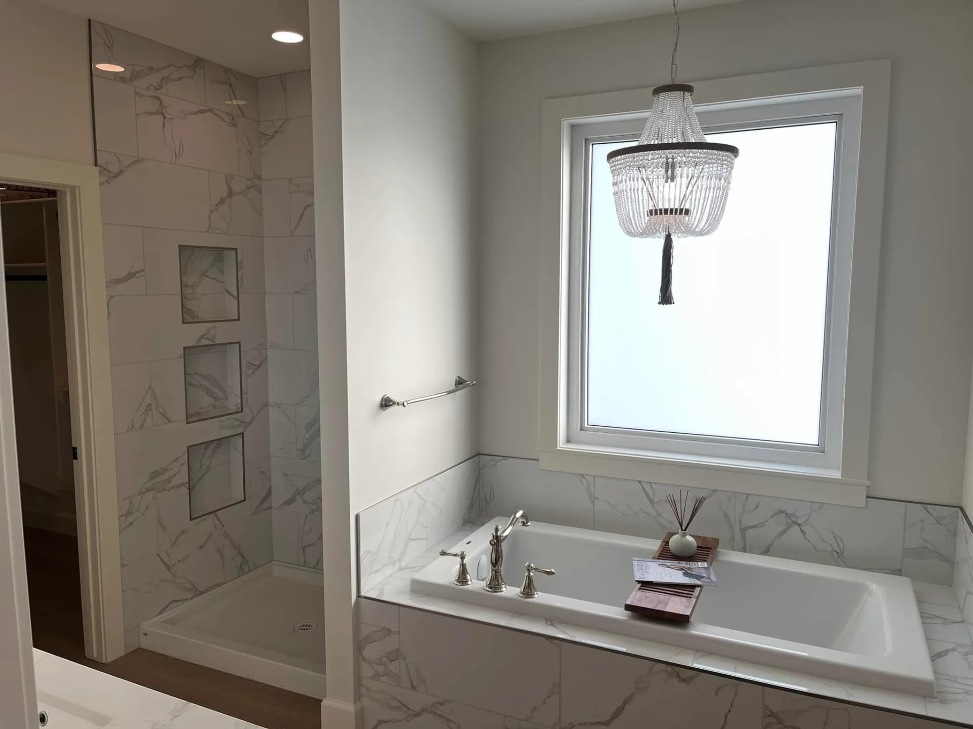 Marble-look tiled shower with recessed niches beside the soaker tub