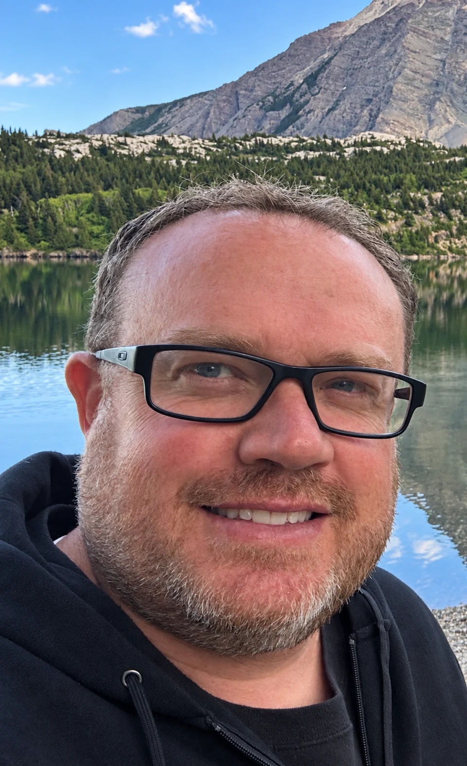 Matt Baines smiling beside a mountain lake