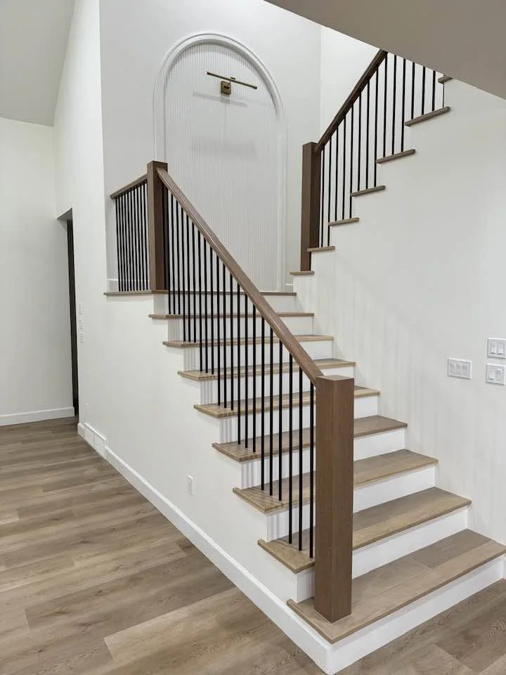 Wood staircase with white risers, slender dark balusters and an arched opening