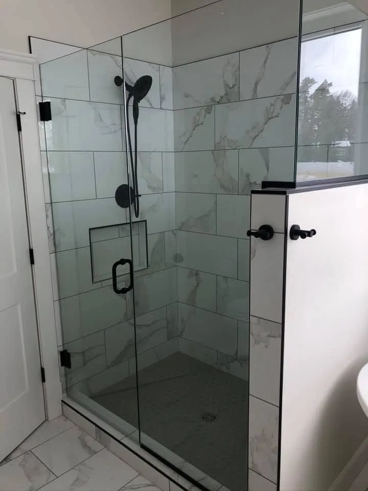 Marble-look tiled shower with black fixtures and a recessed niche
