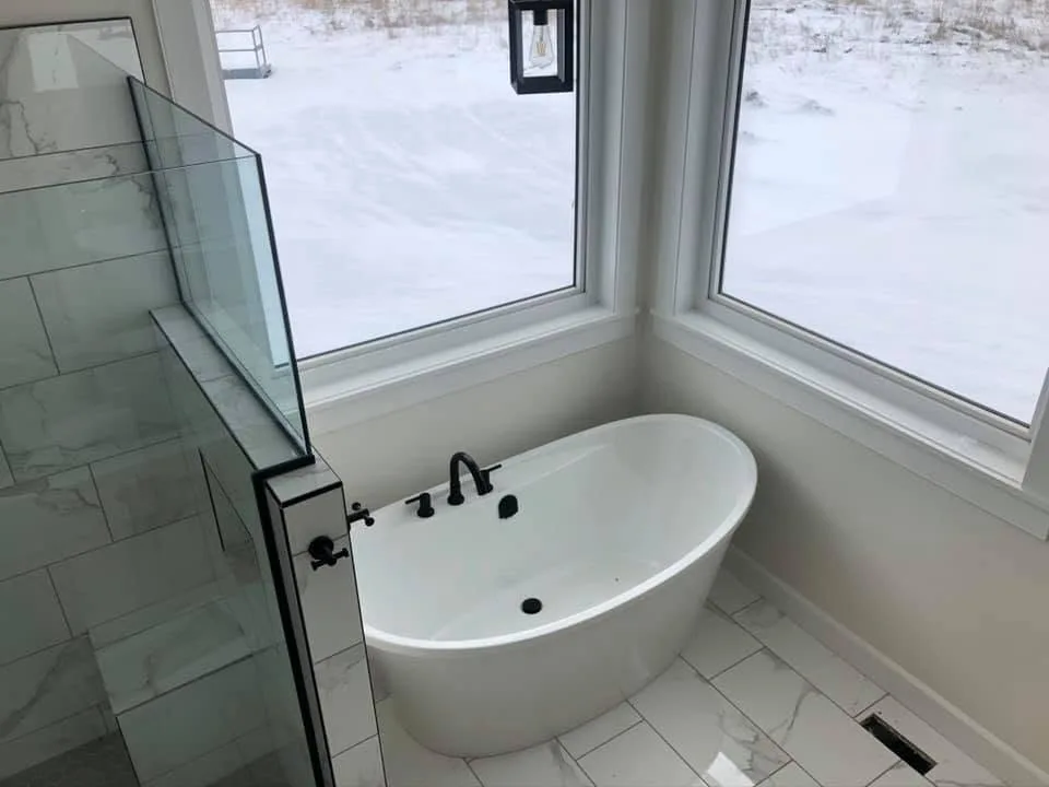 Freestanding tub in a corner of windows beside a glass shower